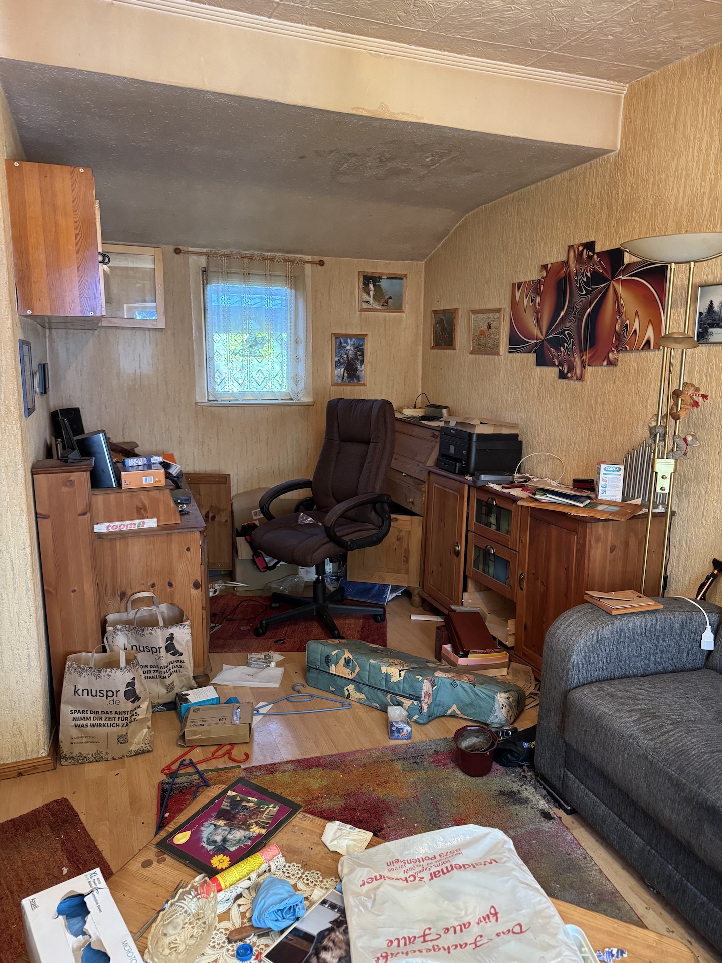 Vorher: vollgestelltes Arbeitszimmer mit Möbeln und Gegenständen auf dem Boden